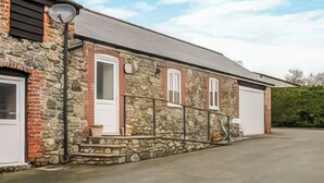 A stone building with a garage, a small porch, and a lamp post. - 1 bedroom accommodation in Llanfair Caereinion (Llanfair Caereinion)