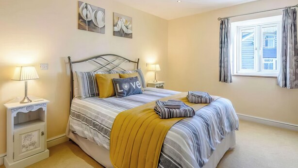 A bedroom with a bed, two bedside tables, a window with curtains, and wall art. - 1 bedroom accommodation in Llanfair Caereinion (Llanfair Caereinion)