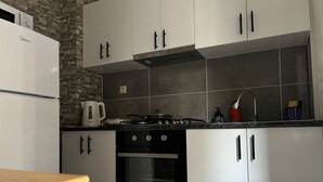 Una cucina con mobili bianchi, un fornello, un forno a microonde e una macchina per il caffè.