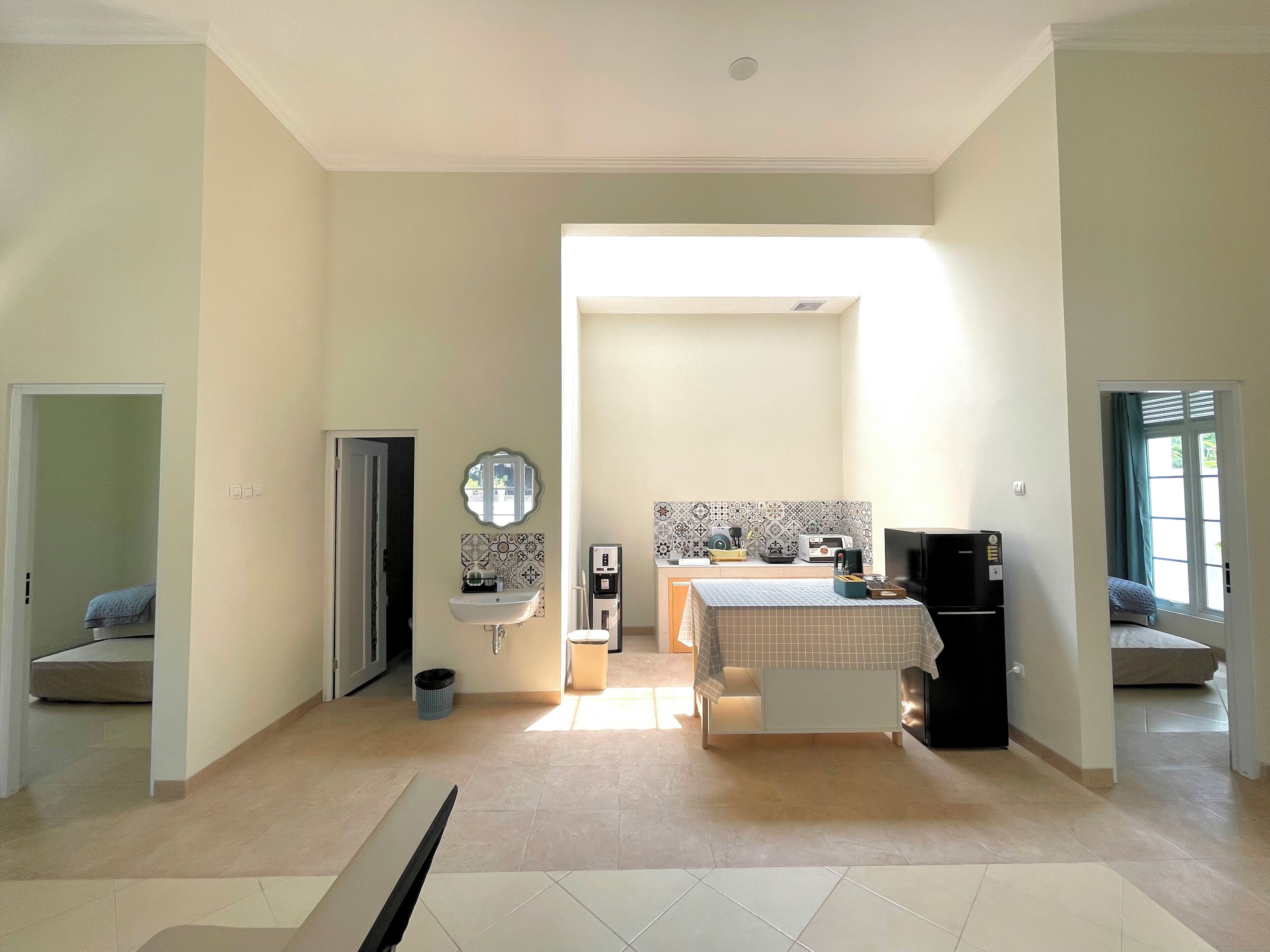 Una habitación amplia con cama, mesita de noche y baño con lavamanos y espejo.