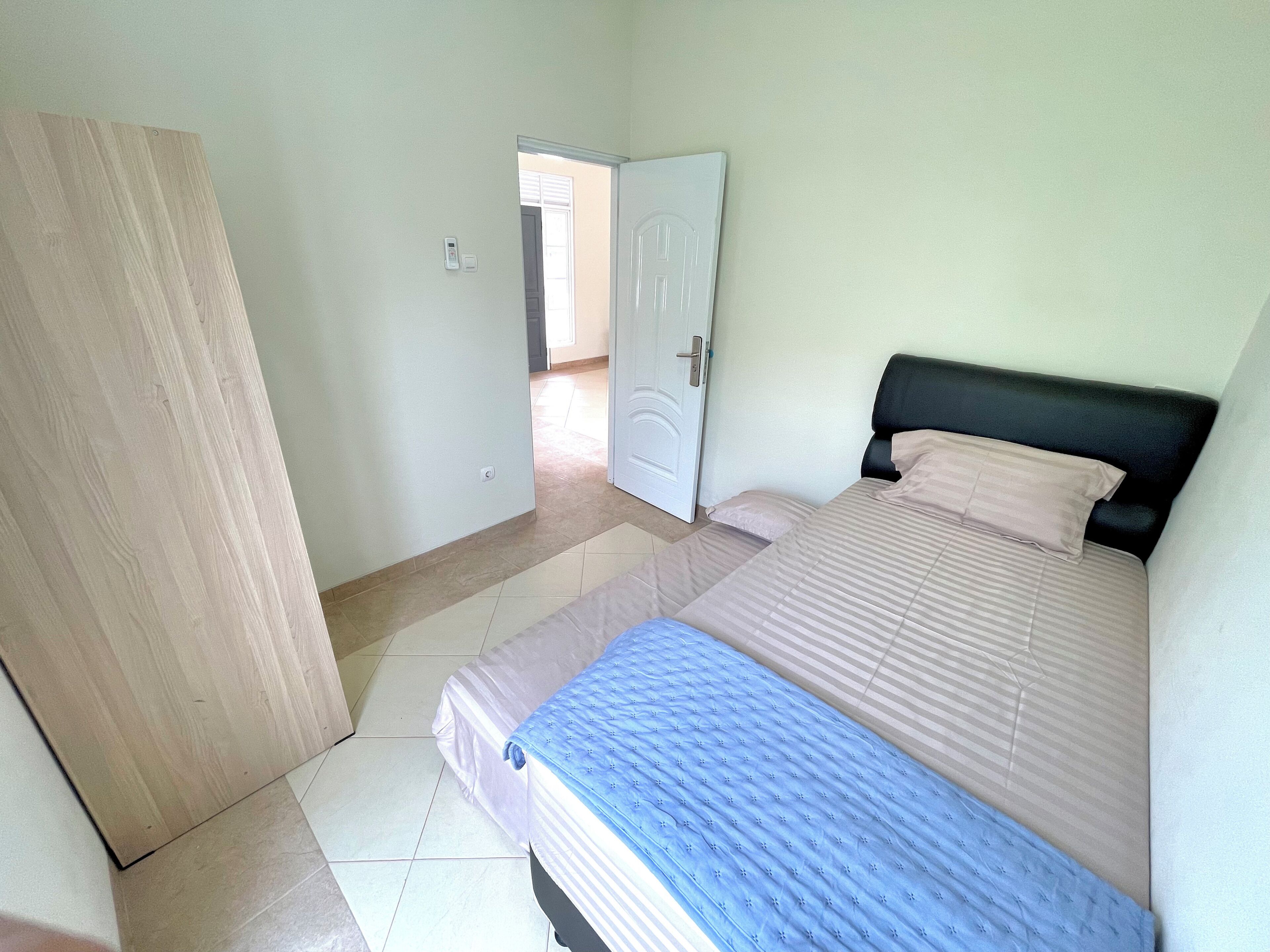 A bedroom with a bed, a door, and a tiled floor.