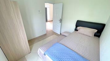 A bedroom with a bed, a door, and a tiled floor.
