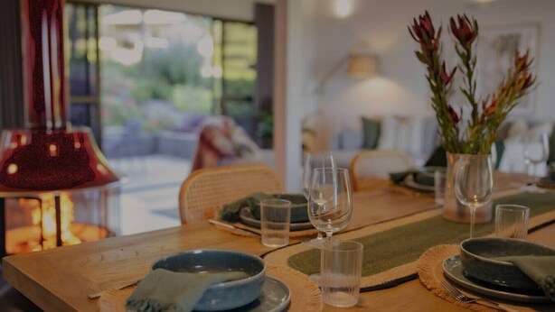 Une table à manger dressée avec des assiettes, des verres et un vase de fleurs.