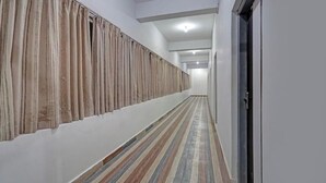 A hallway with striped flooring, a white wall, and a door on the right. - Hotel Sri Krishna Palace (Bhubaneshwar)