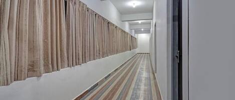 A hallway with striped flooring, a white wall, and a door on the right.