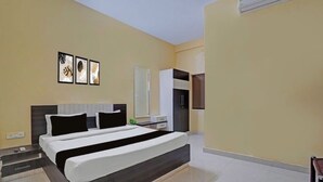 A modern bedroom with a large bed, a bedside table, a wardrobe, and a wall-mounted air conditioning unit. - Hotel Sri Krishna Palace (Bhubaneshwar)