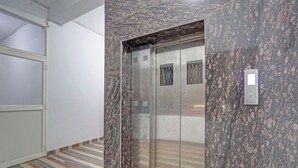 A modern elevator with metallic doors, a marble wall, and a striped floor. - Hotel Sri Krishna Palace (Bhubaneshwar)