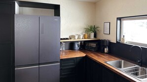 A kitchen with a black refrigerator, wooden countertop, stainless steel sink, and a potted plant. - Rusutsu Tsuru House 2. (喜茂別町)