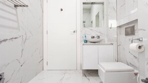 A modern bathroom with a white door, a sink with a mirror above it, and a toilet.