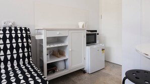A kitchenette with a microwave, refrigerator, and storage cabinets.