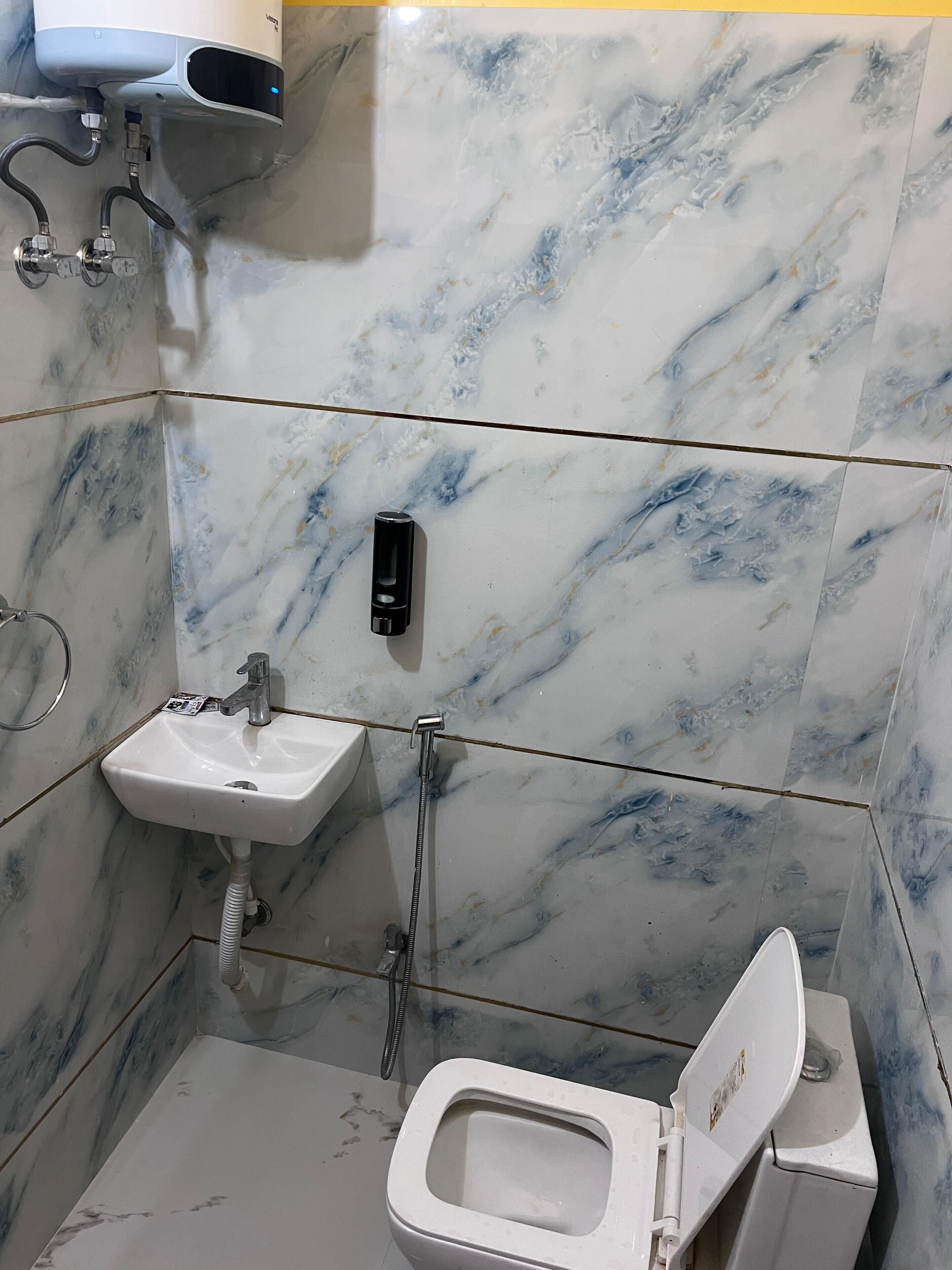 Une salle de bain avec des toilettes, un lavabo et une douche.