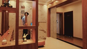 A hotel lobby with a wooden reception desk, a marble wall, and a door marked '100'. - SEA BLISS (Port Blair)