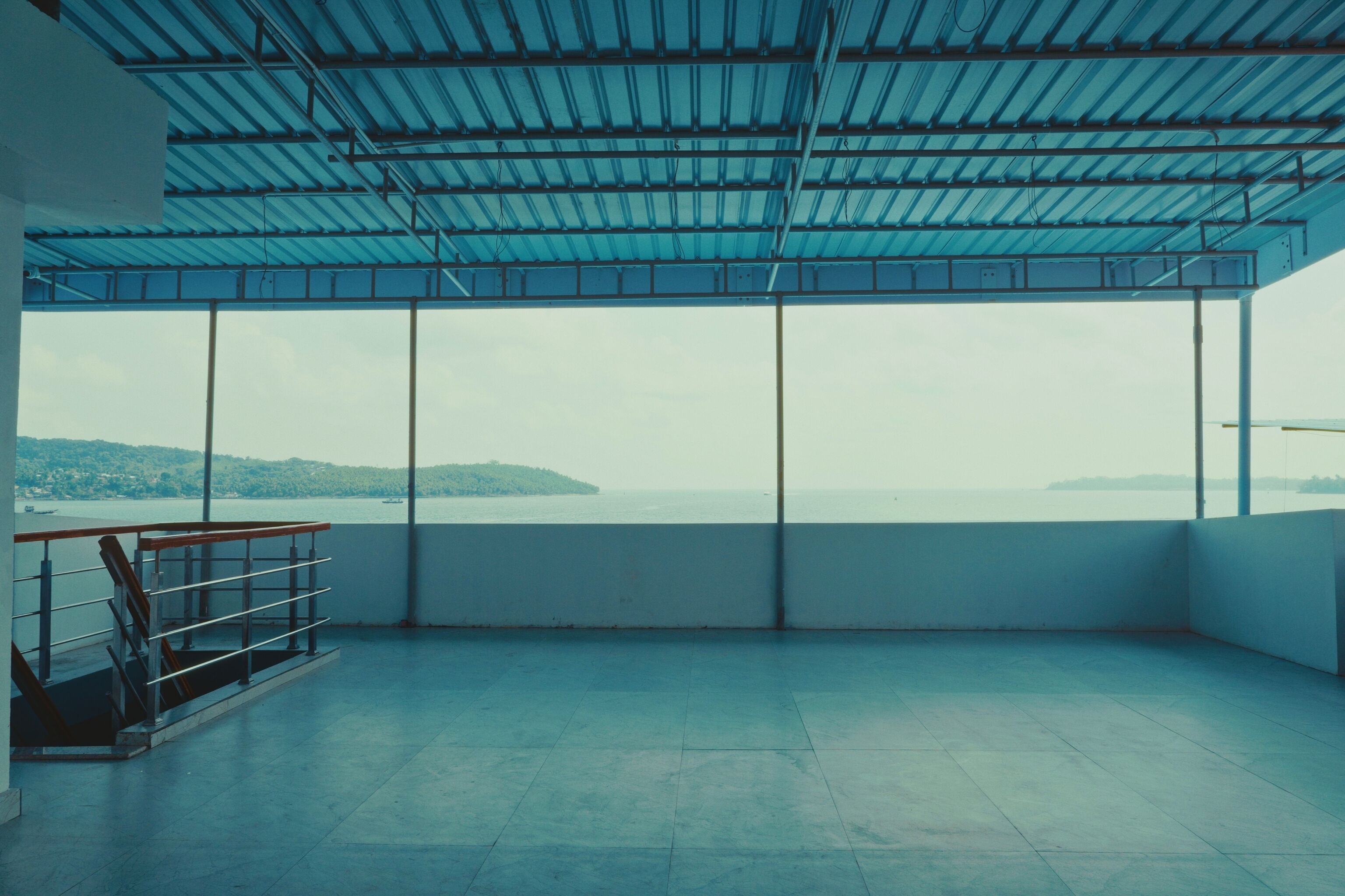 A spacious balcony with a view of the sea and hills.