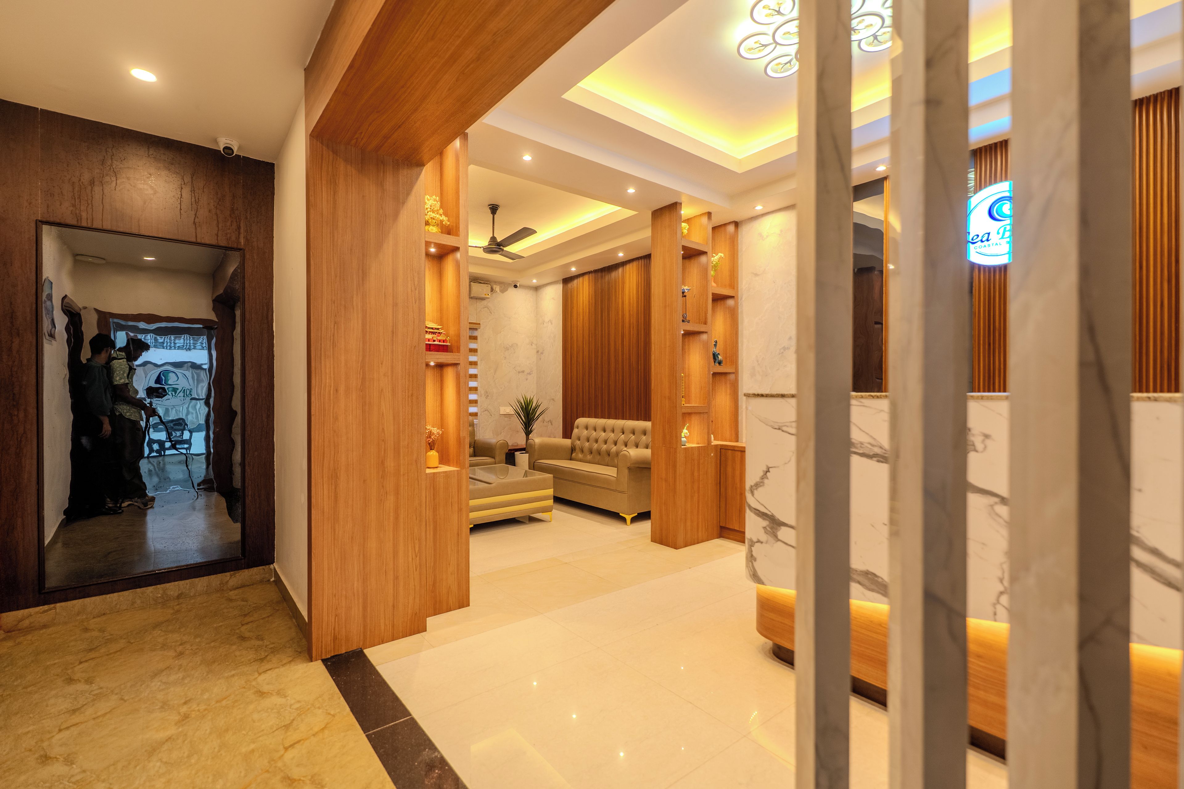A modern interior with a wooden reception desk, a seating area with a sofa, and a marble floor.