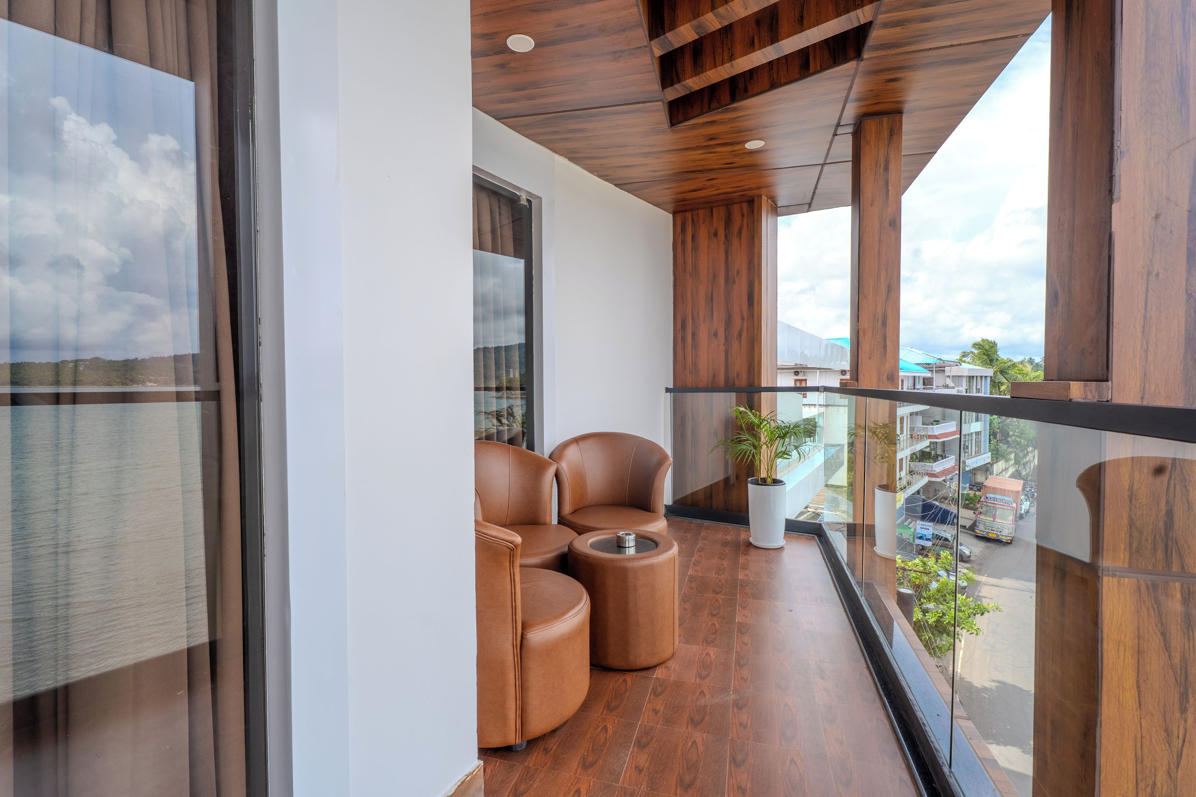A balcony with leather chairs, a potted plant, and a view of the cityscape.