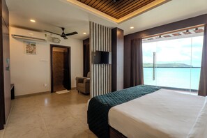 Ein Hotelzimmer mit Bett, Stuhl, Fernseher und Meerblick.