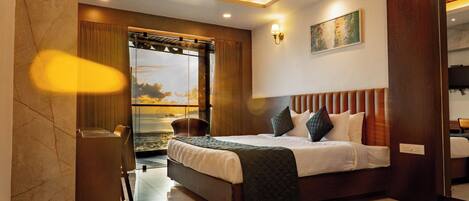A modern hotel room with a large bed, a ceiling fan, a view of the outdoors, and a wooden headboard.