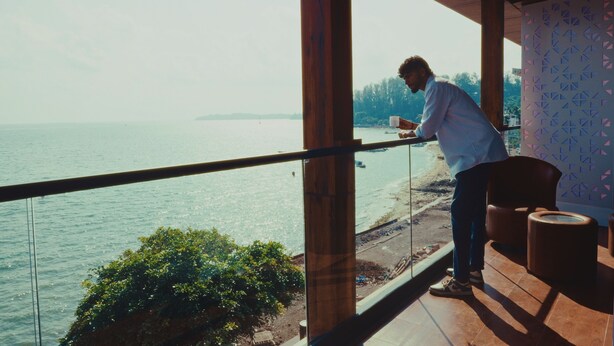 A person standing by a balcony with a view of the sea and a distant island. - SEA BLISS (Port Blair)