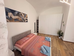 Une chambre à coucher avec un lit, un tableau, une armoire et une petite plante.