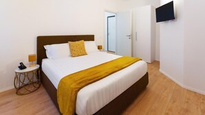 Ein Hotelzimmer mit Bett, Nachttisch und einem an der Wand befestigten Fernseher.