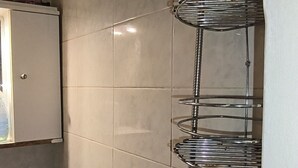 Et badeværelse med brusebad, håndvask og spejl.