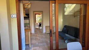 Una habitación con puerta corrediza de vidrio que da a un balcón, un comedor con mesa y sillas, y vistas al exterior.