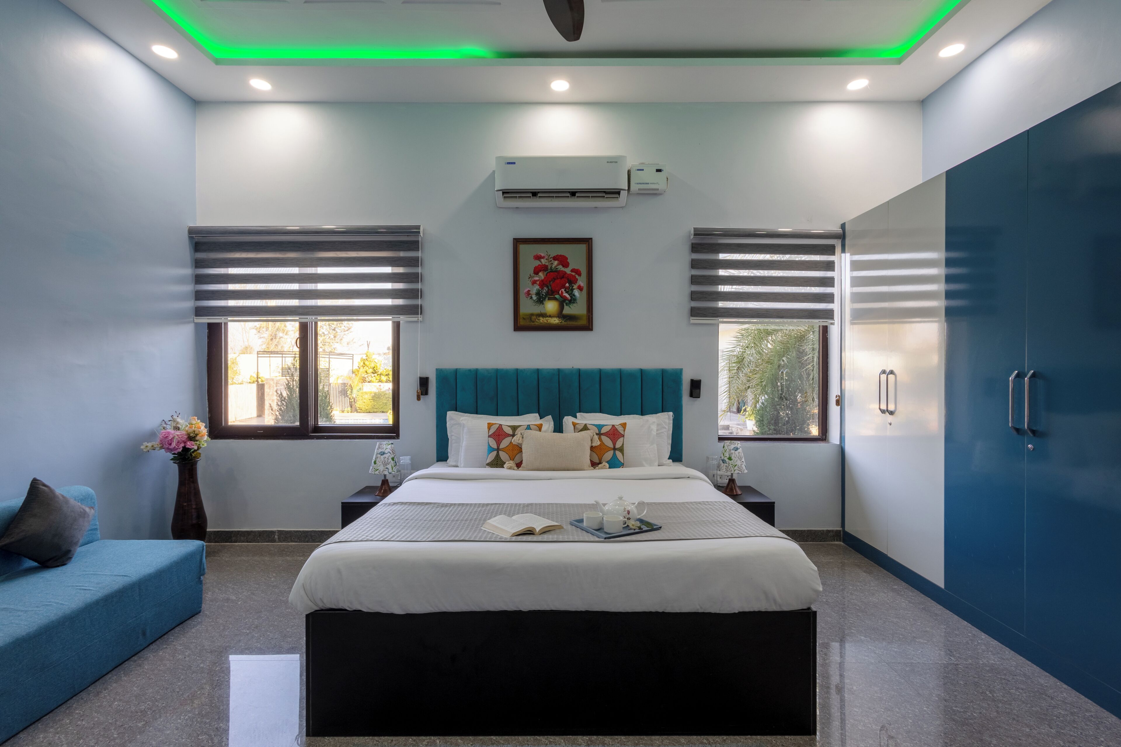 Ein modernes Schlafzimmer mit Bett, Nachttischen, einer Kommode und einem Fenster mit Jalousien.