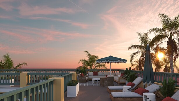 A rooftop lounge with outdoor seating, a view of the sunset, and palm trees. - Beachside Boutique Hotel + Pool + Hot Tub + Rooftop| The Mara by AvantStay (Laguna Beach)
