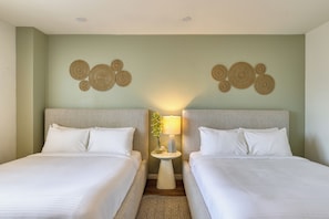 Ein Hotelzimmer mit zwei Betten, einem kleinen Nachttisch mit Lampe, Wanddekoration und einem gemusterten Teppich.