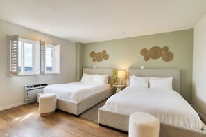 Een hotelkamer met twee bedden, een raam met luiken, een wandairconditioner en een decoratief object aan de muur.