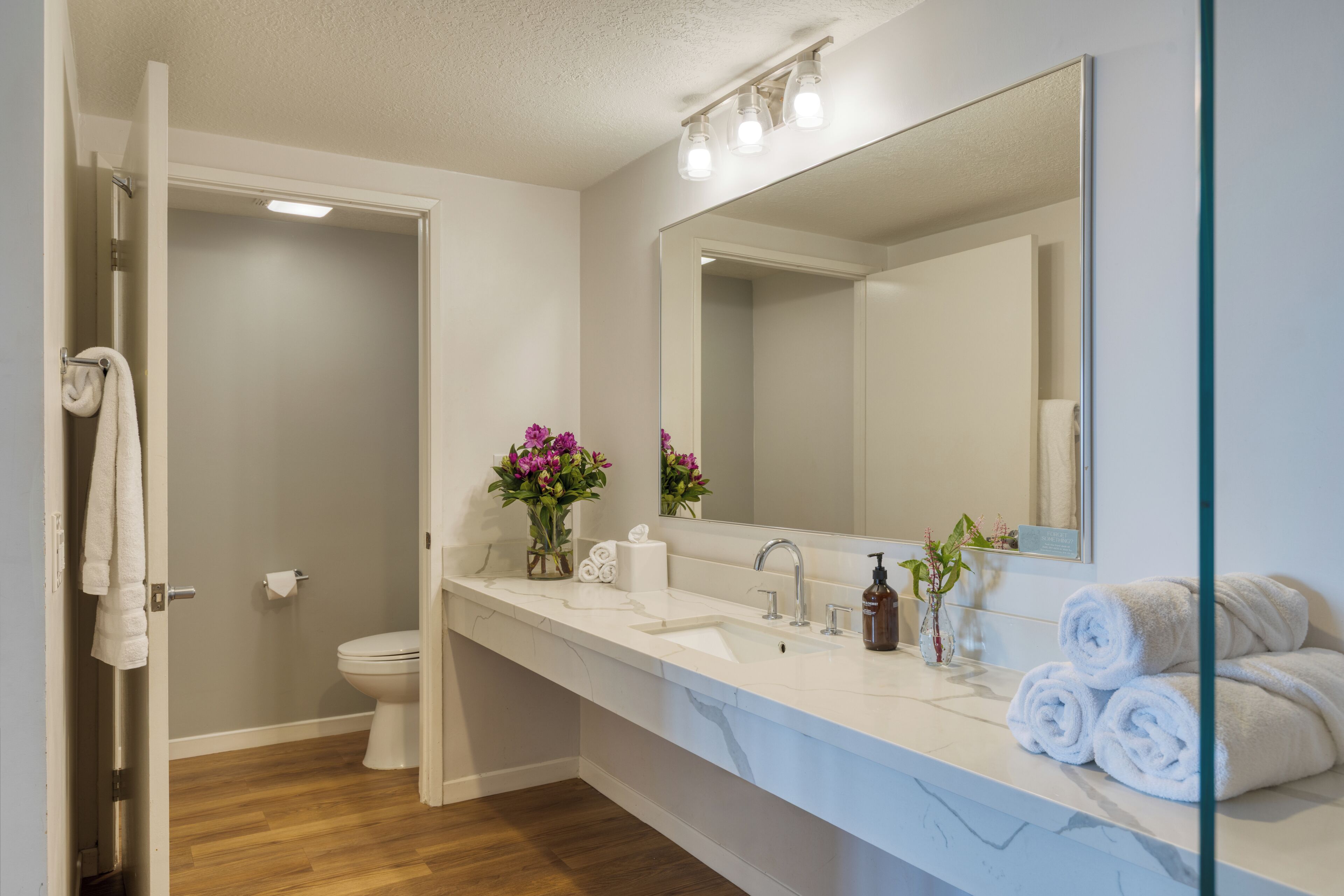 A bathroom with a white sink, mirror, and a shower area.