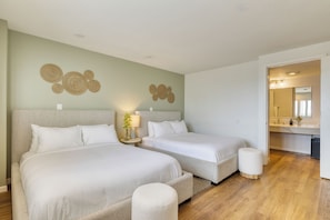 A hotel room with two beds, a small round table, and a mirror in the bathroom. - Rooftop Ocean Views + Spa + Prime Laguna Beach Location | The Mara by AvantStay (Laguna Beach)