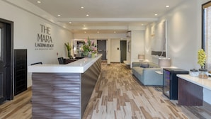 Un hall d’hôtel moderne avec un comptoir d’accueil, un canapé, un réfrigérateur et un téléviseur fixé au mur.