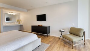 Een moderne hotelkamer met een groot bed, een flatscreen televisie, een klein bijzettafeltje en een bank.