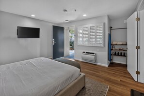 Une chambre moderne équipée d’un lit, d’une télévision, d’une armoire et d’un climatiseur intégré.
