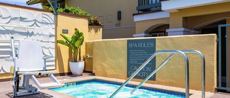 A spa pool with a sign listing rules and a lifeguard chair.