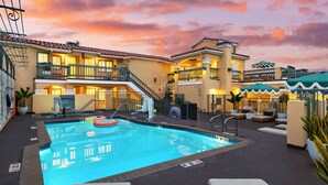 A rooftop pool with a view of the hotel buildings, a lifeguard stand, and lounge chairs.