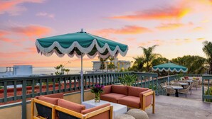Kattoterassi, jossa on ulkotilaa istumiseen, näkymä merelle ja upea auringonlaskun taivas.