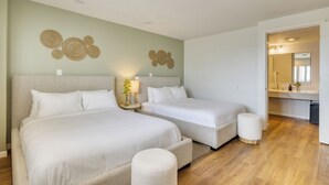 Ein Hotelzimmer mit zwei Betten, einem kleinen runden Tisch und einem Spiegel im Badezimmer.
