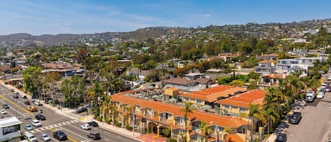 A residential area with a street, parked cars, and a row of houses with orange roofs.