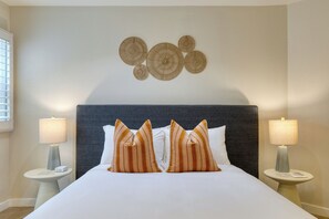 A hotel room with a large bed, two bedside tables with lamps, a dark headboard, and a wall decoration above the bed. - Boutique Stay + Pool + Hot Tub + Rooftop | Walk to Beach + Dining + Galleries (Laguna Beach)