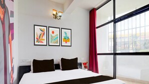 A modern hotel room with a large bed, a city view, and three framed artworks on the wall. - Deluxesree Residency (Bengaluru)