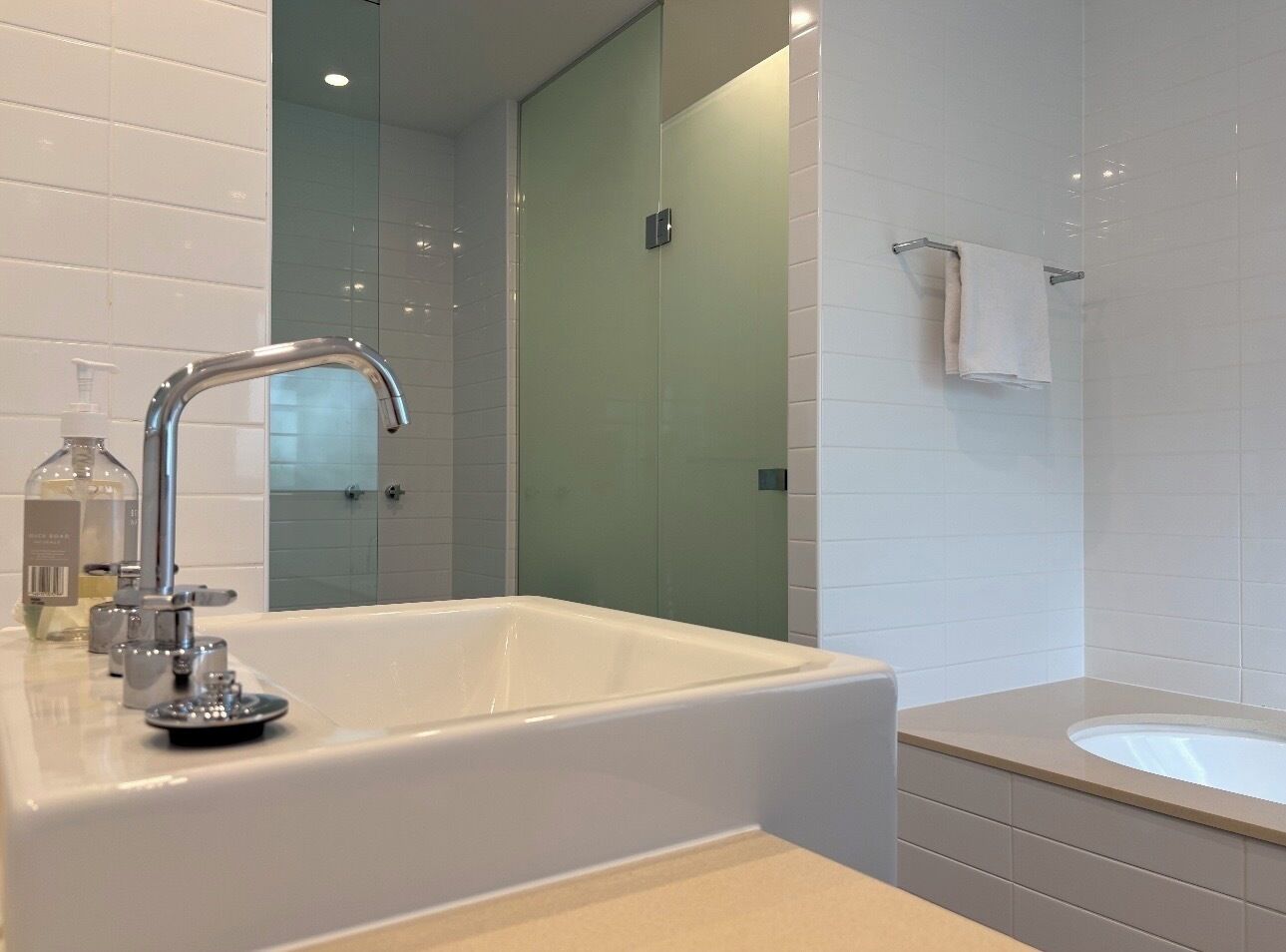 A modern bathroom with a large white bathtub, a separate sink, and a glass-enclosed shower.