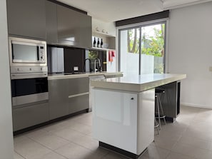 Eine moderne Küche mit Edelstahlgeräten, einem Einbauofen und einem kleinen Kühlschrank.