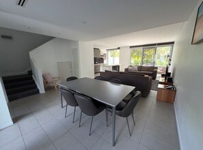 Ein modernes Interieur mit einem Esstisch, Stühlen, einer Couch und einer Treppe.