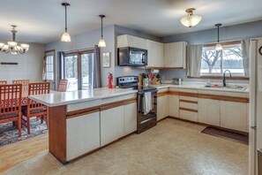 A kitchen with a central island, a microwave, oven, and a sink.