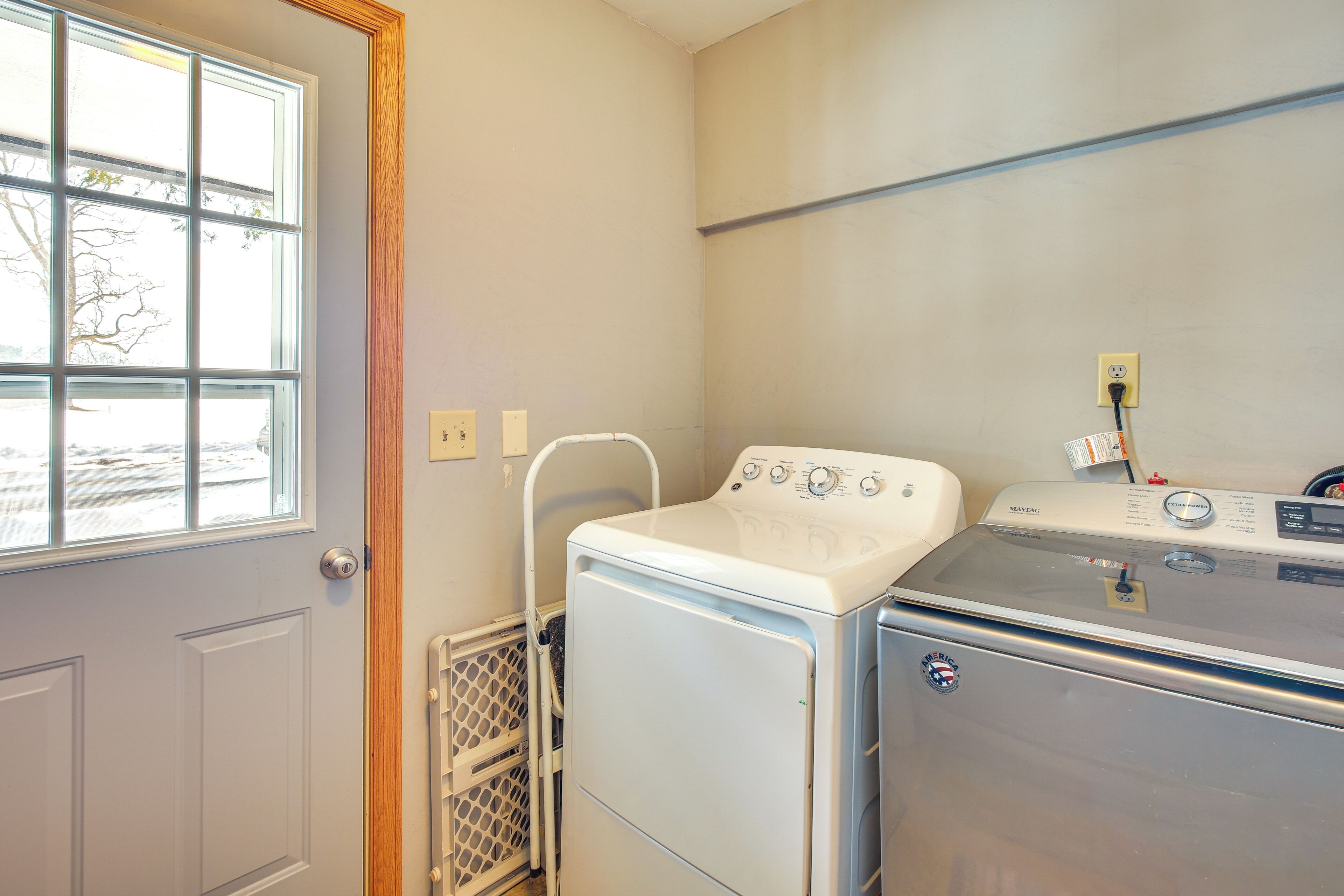 A laundry room with a front-loading washer and dryer, a window, and a door.