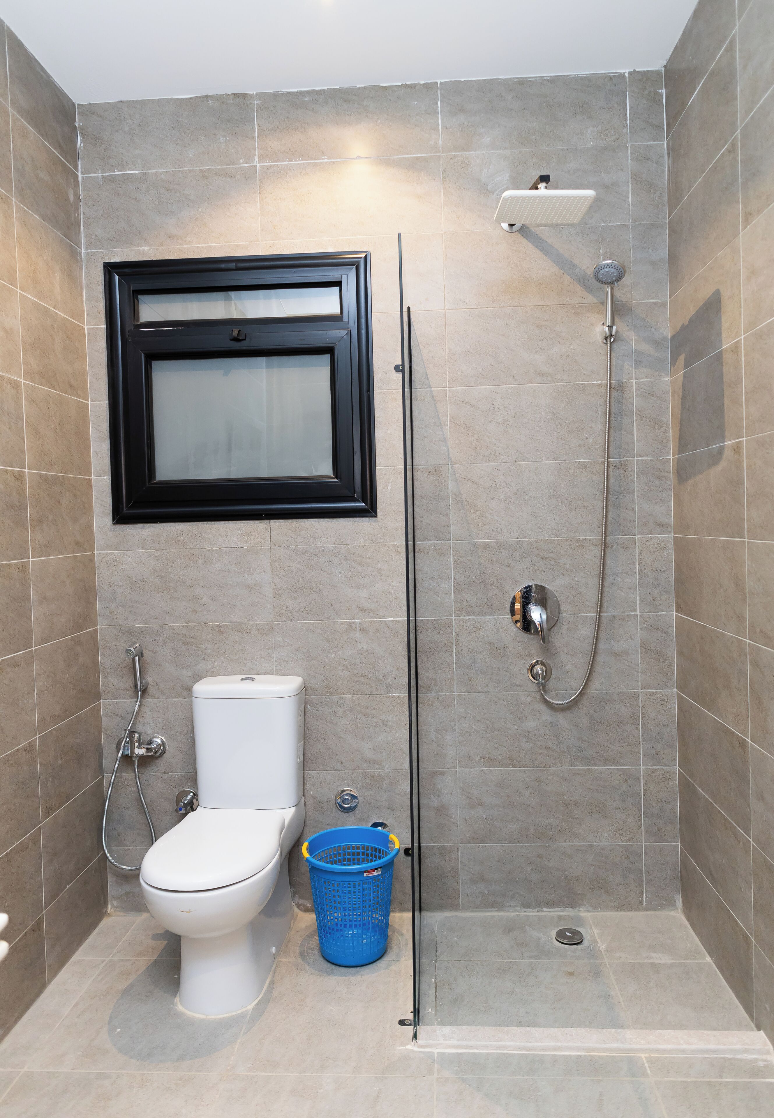Un baño con inodoro, ducha y una cesta azul.