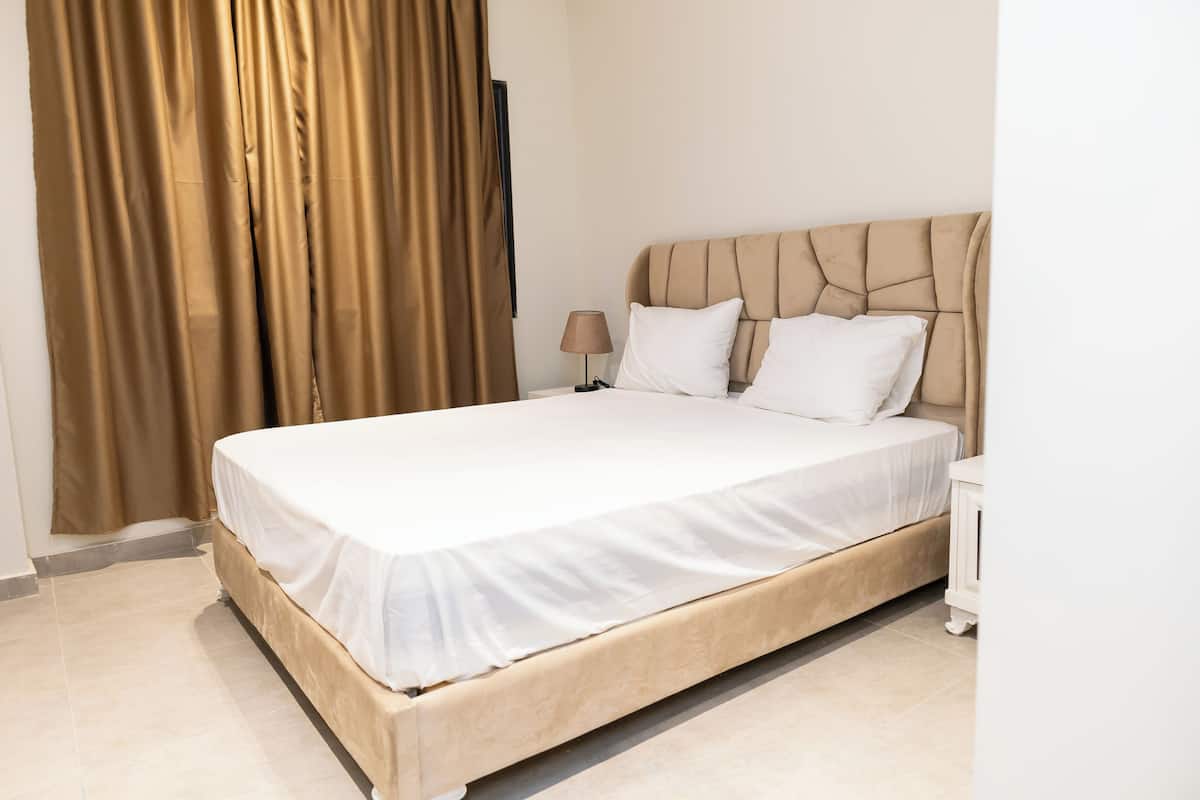 Una habitación de hotel con una cama grande, una mesita de noche, una lámpara y un televisor en la pared.