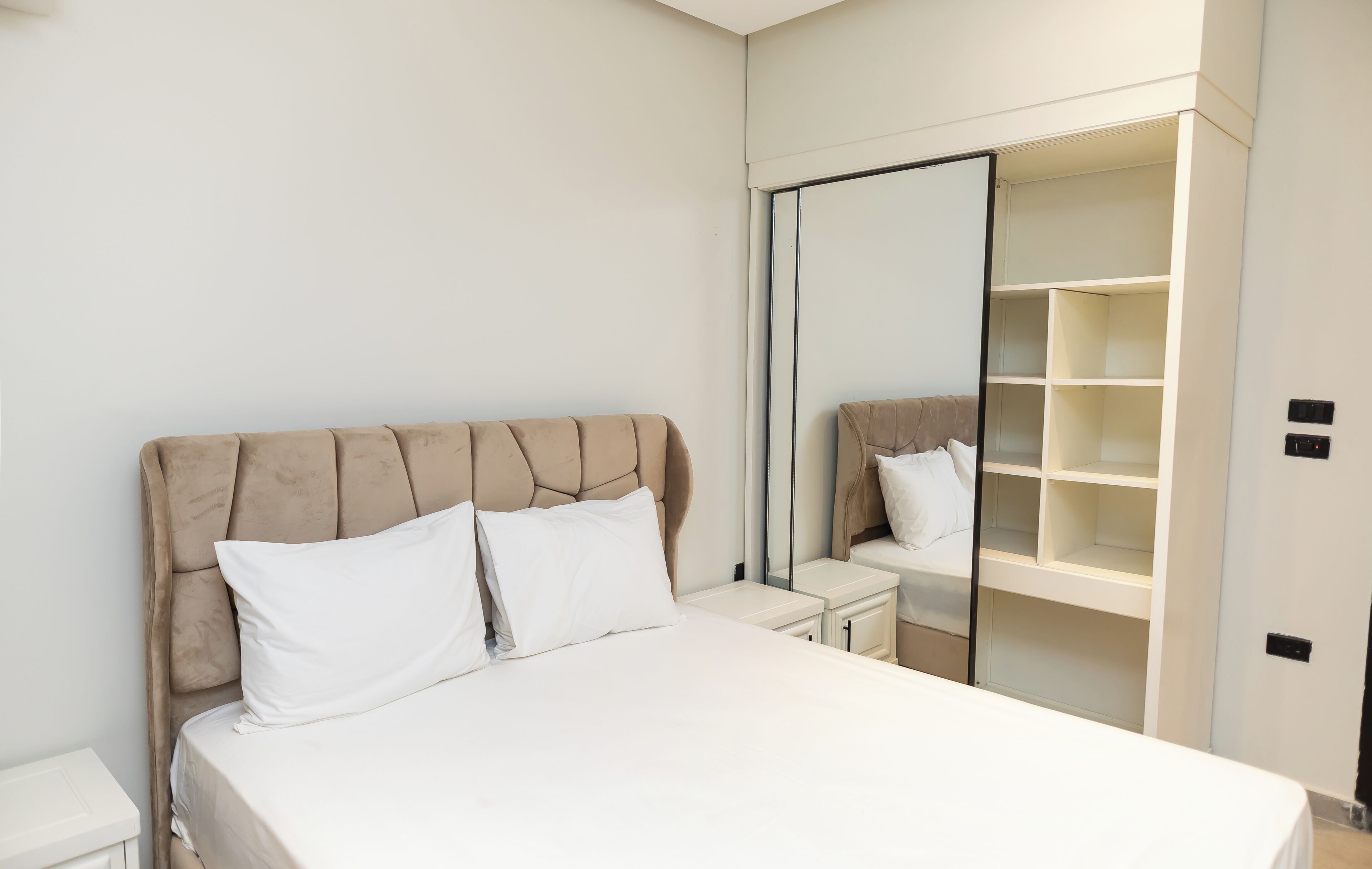 Un dormitorio con cama, mesitas de noche, armario y espejo.